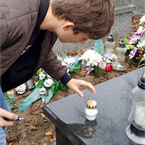 Uczeń klasy 6b zapala znicz na grobie ojca J.A.Maklakiewicza