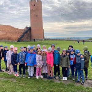 Grupa uczniów różnej płci stojących przed wejściem do Zamku w Czersku.