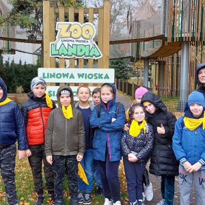 Grupa uczniów wraz z wychowawczyniami, za ich plecami znajduje się park linowy  Łódzkiego Zoo.