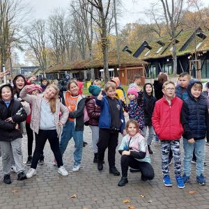 Grupa uśmiechniętych uczniów tańczących na jednej z alejek Zoo.