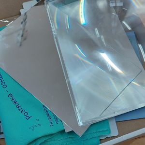 Otwarte białe pudełko, w którym znajduje się niebieski materiał z instrukcją oraz szkła powiększające.
