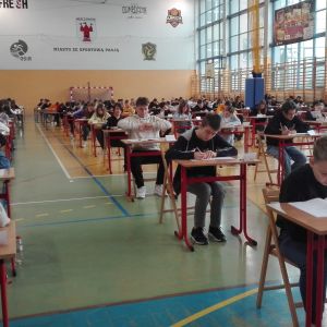 Uczniowie siedzący w pojedynczych ławkach i piszący próbny egzamin.