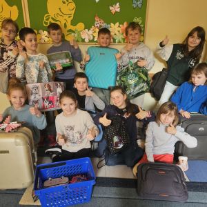 Otwórz zdjęcie - Uczniowie klasy 2 trzymający w górze kciuki i ich pomysły na kreatywne spakowanie książek.