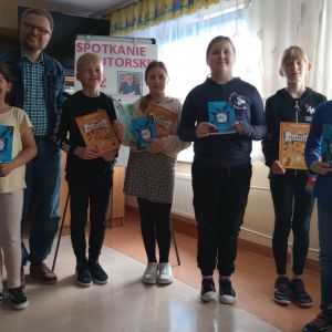 Otwórz zdjęcie - grupa uczniów pozująca do zdjęcia wraz z pisarzem.