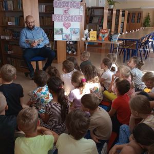 Otwórz zdjęcie - Tata jednego z uczniów czyta książkę dzieciom.