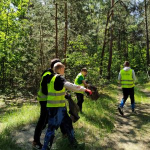 Otwórz zdjęcie - Chłopcy z klasy 6d zbierają śmieci do worków w lesie.