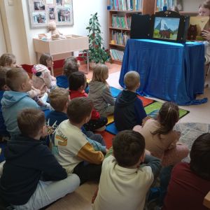 Otwórz zdjęcie: Uczniowie 2D siedzą na dywanie i słuchają teatrzyku.