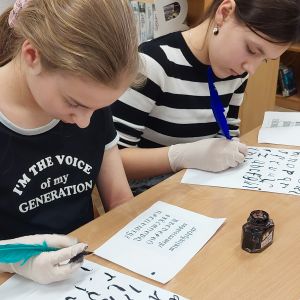 Otwórz zdjęcie -  Dziewczęta przepisują piórem na kartkę bardziej skomplikowane znaki.