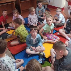 Otwórz zdjęcie - Uczniowie z klasy IE pracują w grupach na dywanie.