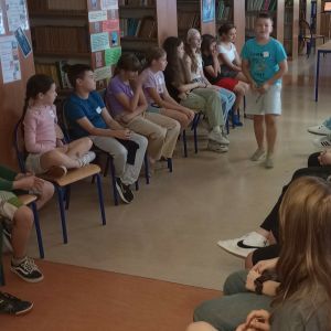 Otwórz zdjęcie -  Uczniowie prezentują się pozostałym uczestnikom zajęć siedzącym w dwóch rzędach na krzesłach.