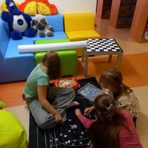 Otwórz zdjęcie - Trzy uczennice siedzące na dywanie i układające puzzle na specjalnej macie.